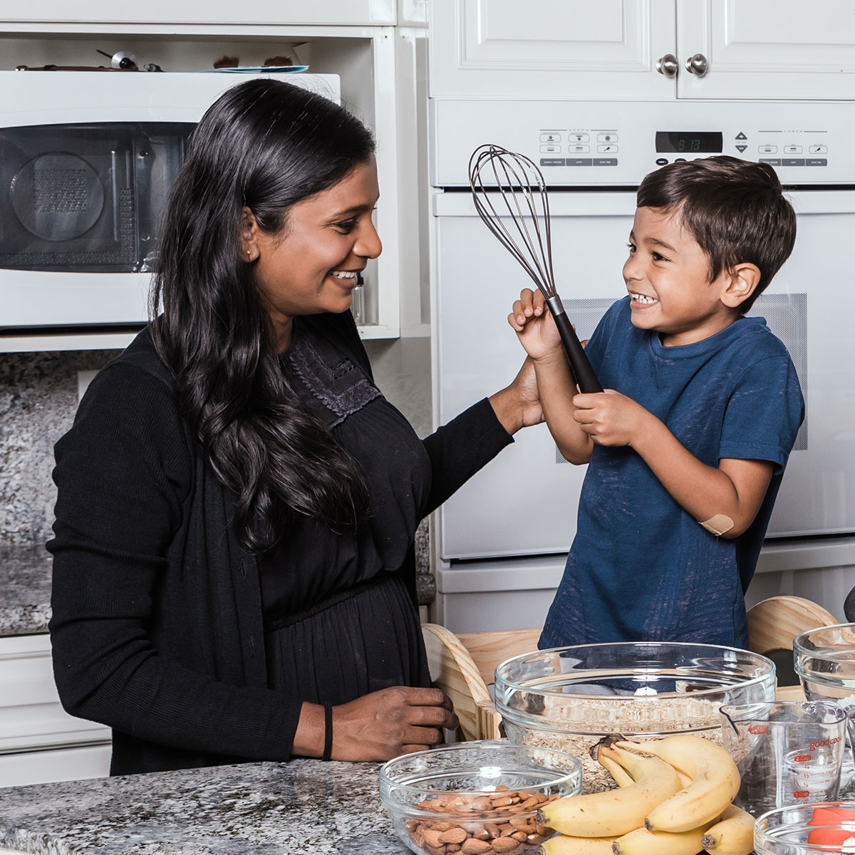 Little Red Wagon Granola Owner, Ven, and her son smiling at each other in the kitchen as they make granola butter