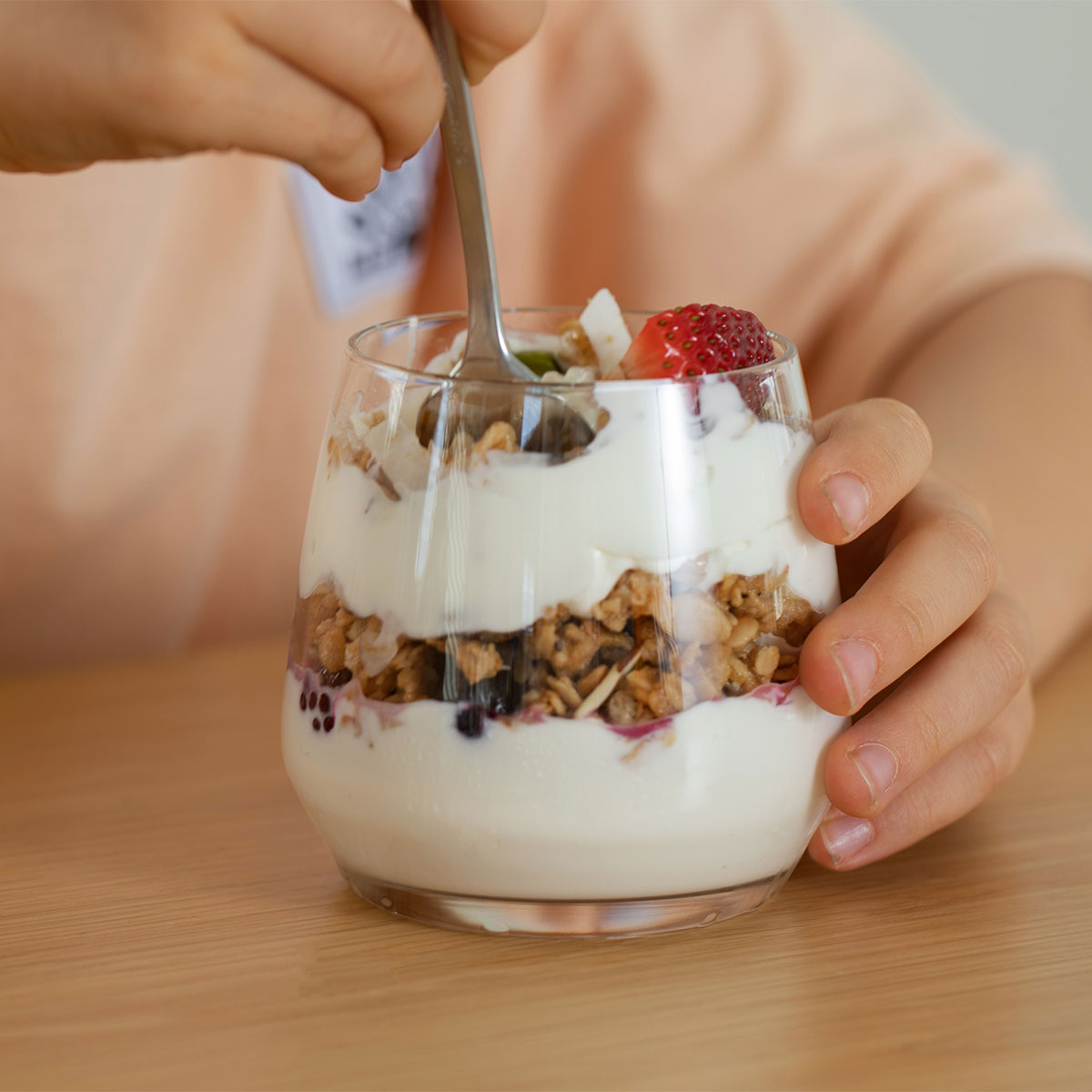 Granola breakfast ideas: child eating a granola, yogurt, parfait